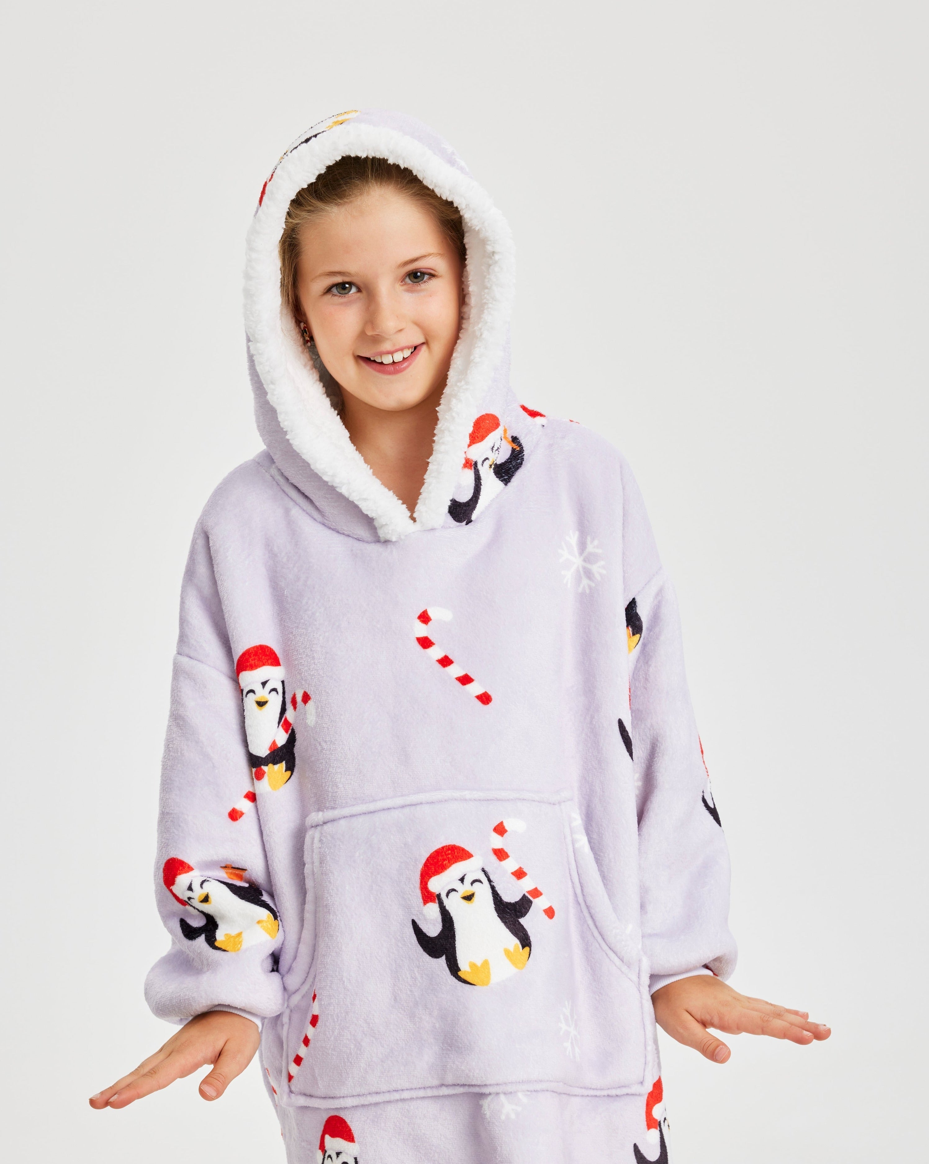 Un enfant portant un sweat à capuche de Noël violet clair avec des pingouins dessus.